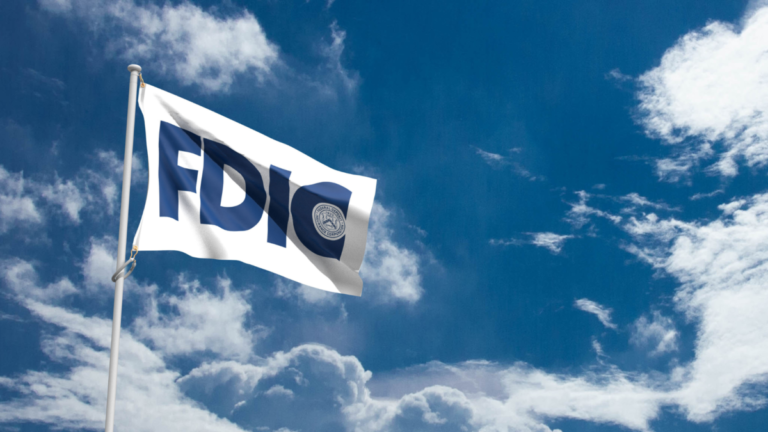 A white flag with the blue FDIC logo on it in a sky with clouds.