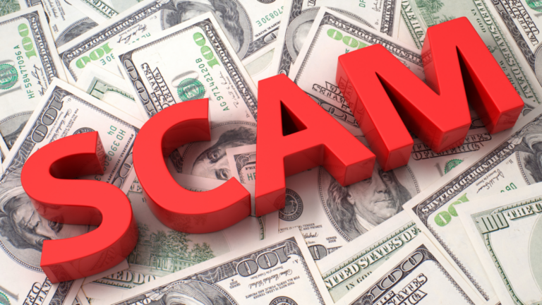 An image of the word SCAM in red blocks laying across money.