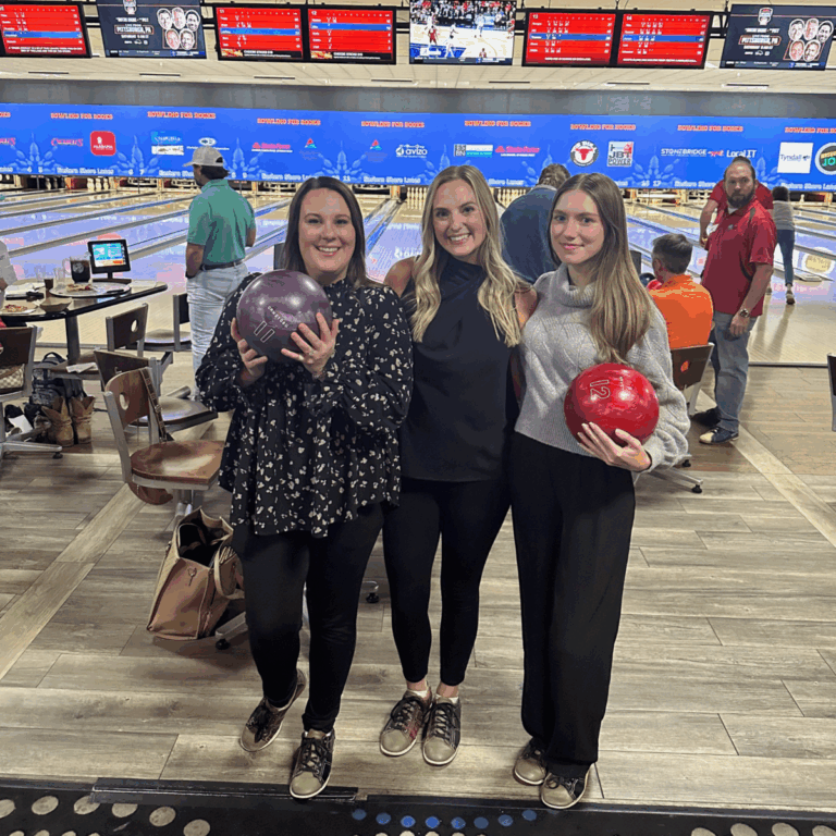 Three Avizo employees smiling and holding bowling balls.