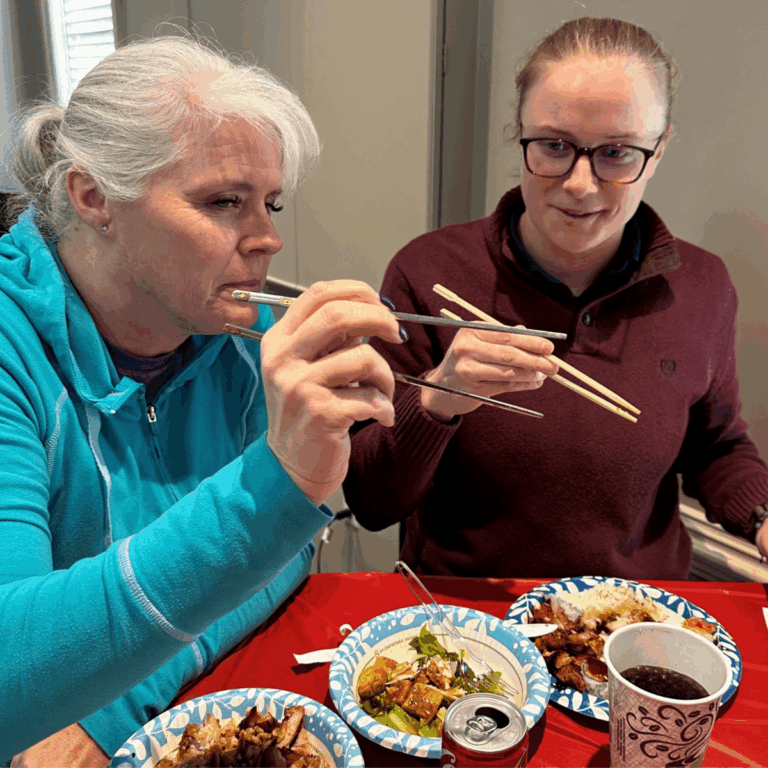 Two Avizo employees learning how to hold chopsticks correctly
