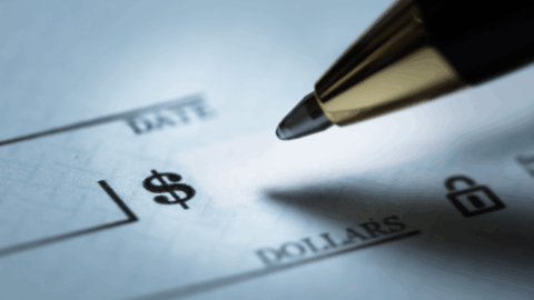 A close up image of the tip of a pen hovering over the "amount" box on a check.