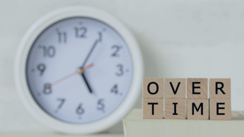 A white background with a clock and in the forefront are wooden blocks that say "Overtime"
