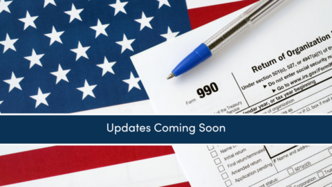 A close up of an image of a 990 tax return on top of an American flag with a pen on it.