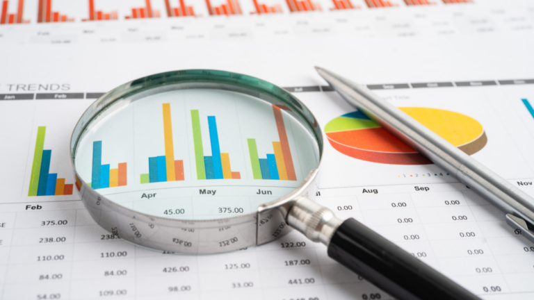 A magnifying glass on a print-out of monthly overview of finances and trends