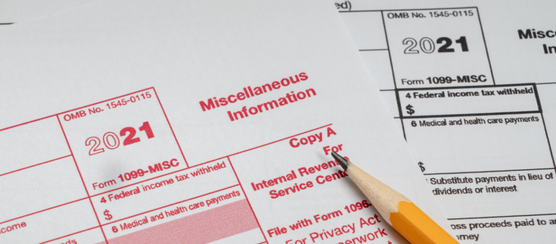 A filing copy and an employee copy of a 2021 MISC 1099 with a pencil laying on top of them