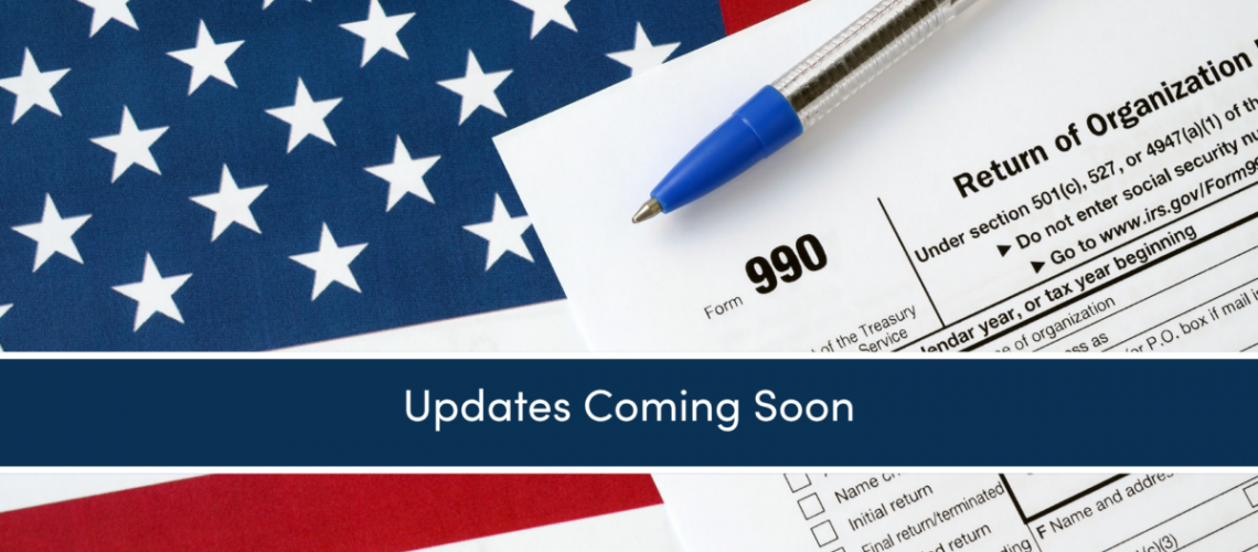 A close up of an image of a 990 tax return on top of an American flag with a pen on it.