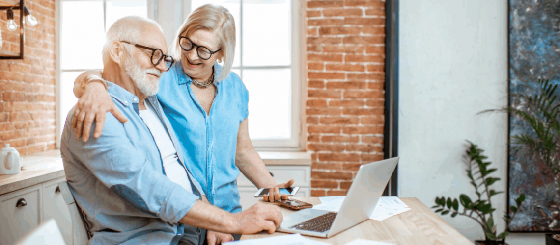 An elderly couple looking at a computer screen and smiling