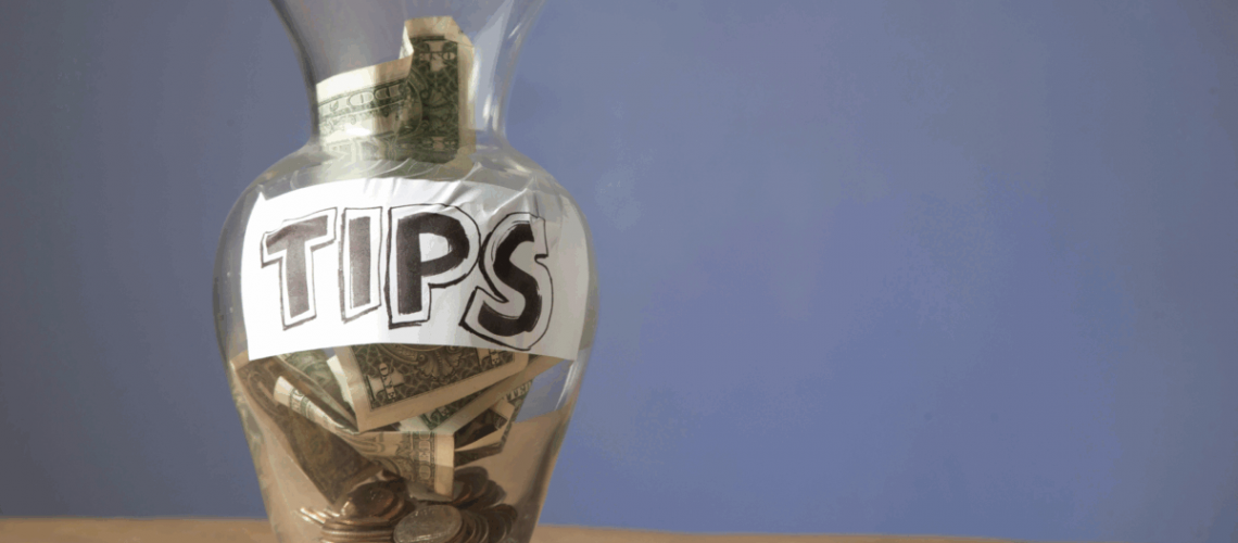 An image of a jar with money in it and a handwritten label that says "tips"
