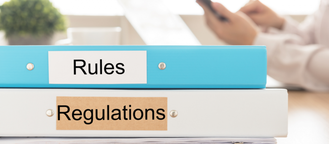 a photo of two stacked binders, one saying "rules" and the other sayin "regulations"