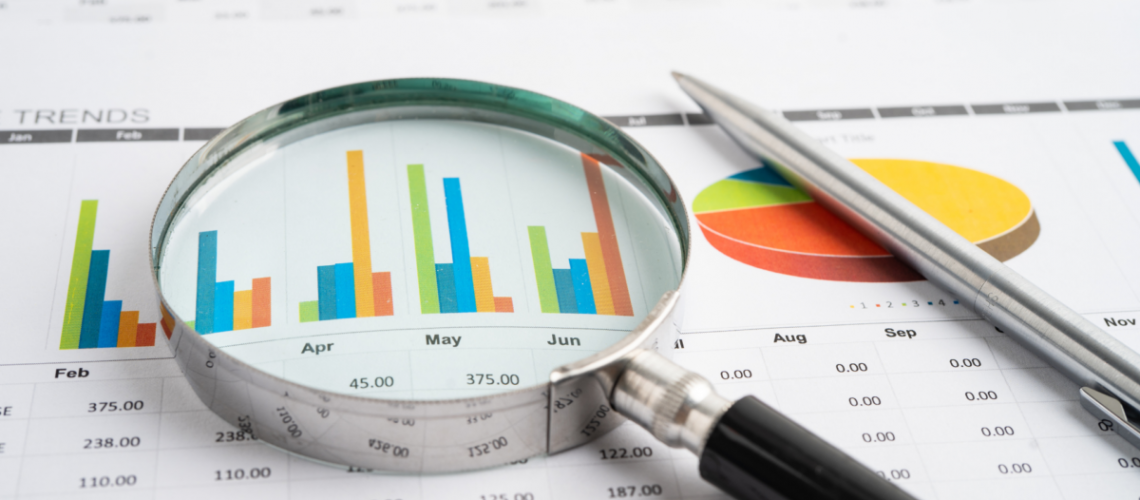 A magnifying glass on a print-out of monthly overview of finances and trends