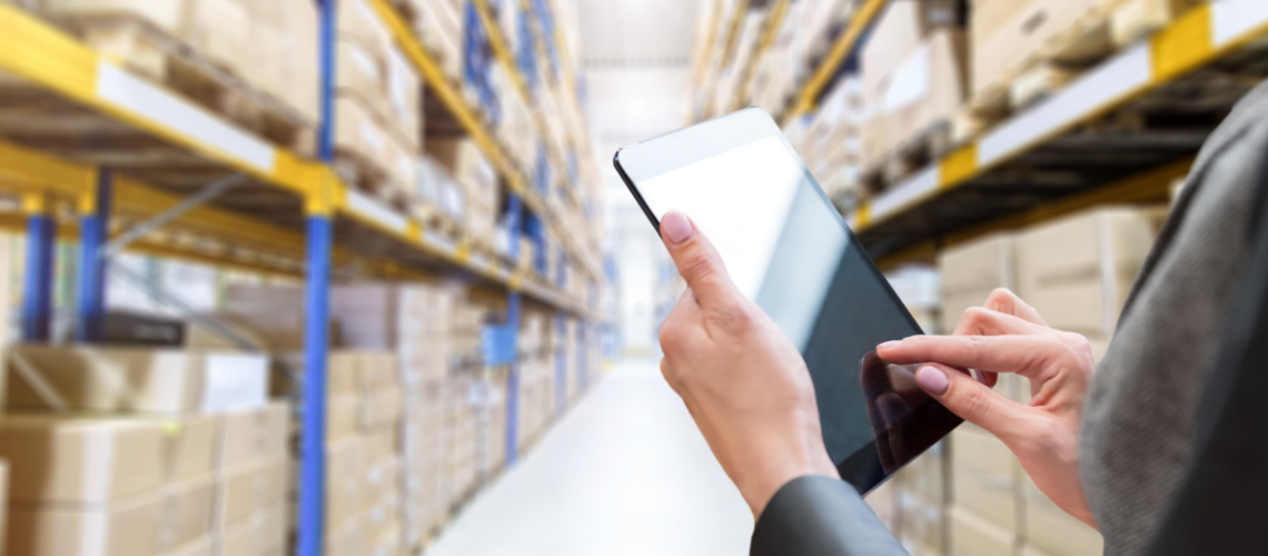 A close-up of a woman holding an ipad in a warehouse