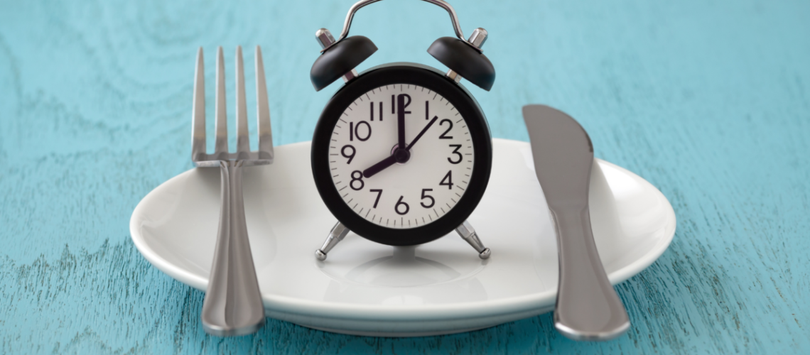 A blue background. In the middle is a plate with a clock on it. On the left is a fork and on the right is a knife.