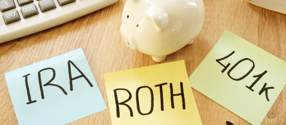 A desktop with a piggy bank and three sticky notes that say "IRA", "ROTH" and "401(k)